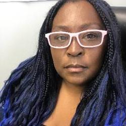 A headshot of an artist with blue braids and glasses