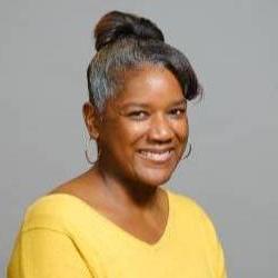 A headshot of an artist in a yellow blouse with her hair pulled back